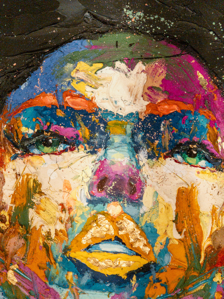 straight on portrait womans head looking up with green eyes multicolored face painted thick and abstract with black splatter hair and gold foil