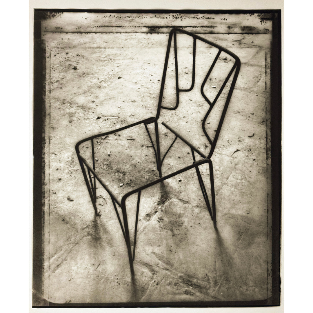 eerie printed image of steel metal chair casting shadows of lines and gradients in grey silver tones