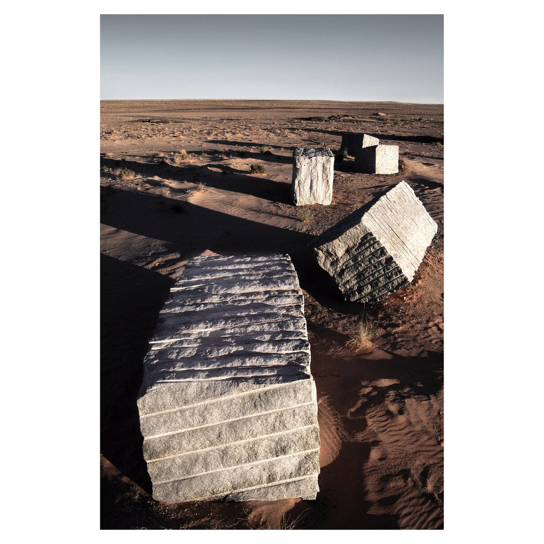 granite blocks in a vast dirt quarry field cube rectangular shadows casting and blue sky on the horizon