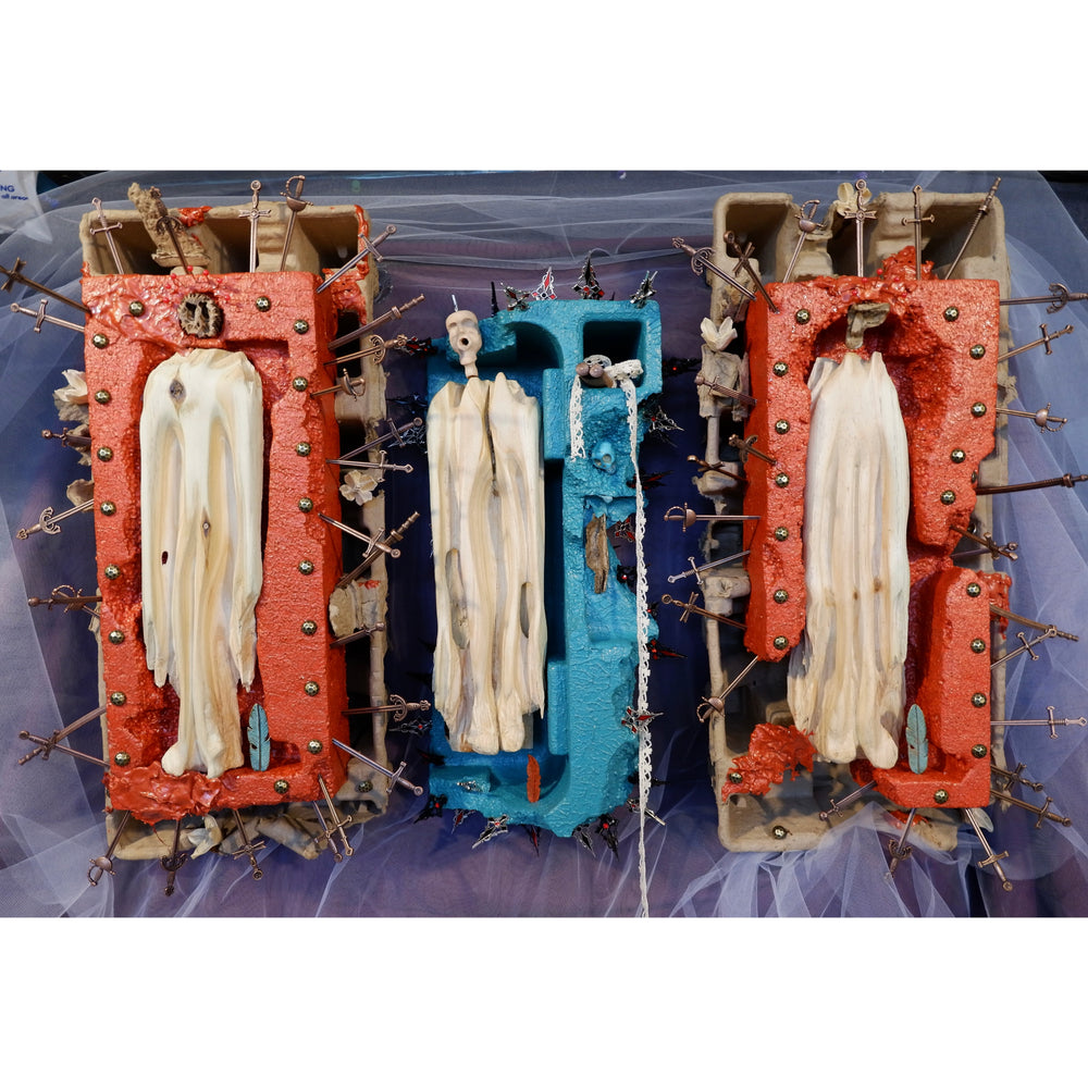 cartons with wooden carved figurines and metal sword crosses sticking out on top purple and white tulle fabric red and blue paint idols