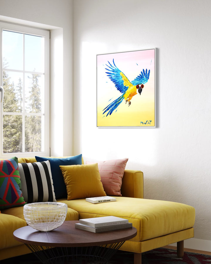 30” x 30” painting by French artist Moogly of a blue and yellow parrot in sunglasses with a pink and yellow ombre background. The parrot is depicted in mid-flight and made out of resin, giving it a textured and shiny finish. The sunglasses are real round, reflective sunglasses that the artist has adhered to the canvas.