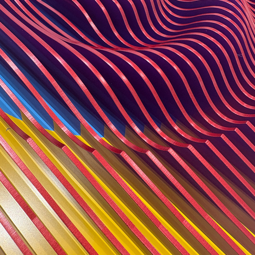 vertical stripes plexiglass abstract geometric with yellow and orange in back and pulsing round circular middle in blue when viewed at angle mostly red