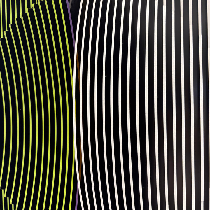 vertical stripes in black and yellow with circle in center offset optical illusion stripes with pink purple stripe down the middle