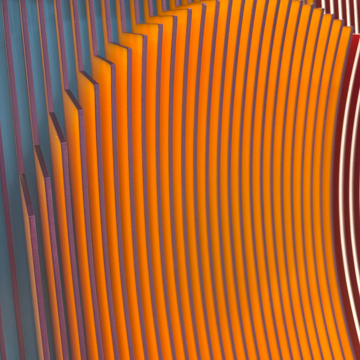 vertical stripes plexiglass abstract geometric with yellow and orange in back and pulsing round circular middle in blue when viewed at angle mostly red