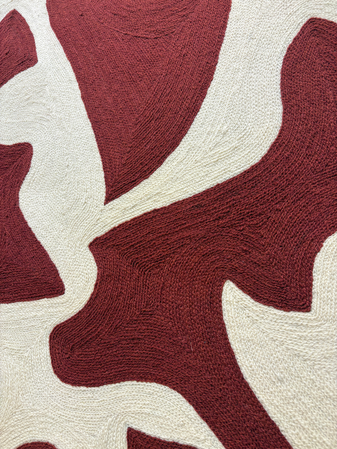 abstract shapes in rust orange red color on cream white background embroidery textile chain stitched design negative space shapes and patterns 