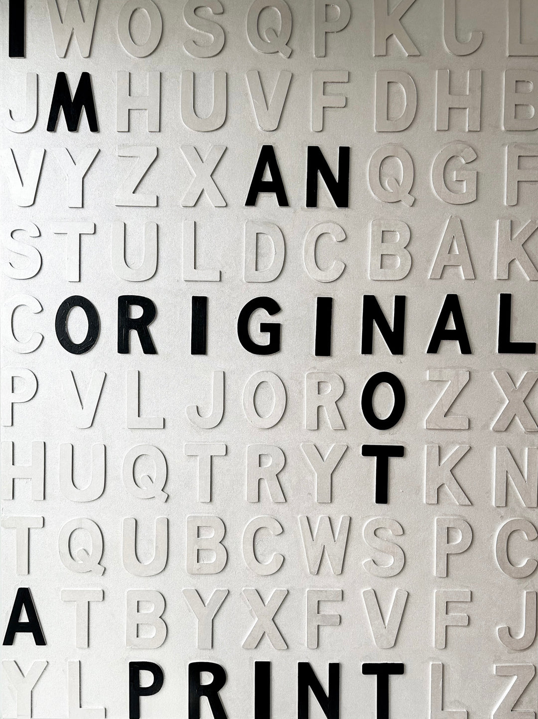 Contemporary 3D text artwork by Chicago artist Steffanie Gerkin titled I’m an Original 3D, featuring raised black and white wood letters arranged in a structured alphabet grid on a white canvas. The monochrome typographic composition spells the phrase “I’m an Original, Not a Print,” creating a bold conceptual wall art piece with graphic text-based design, pop art influence, and contemporary mixed-media style.