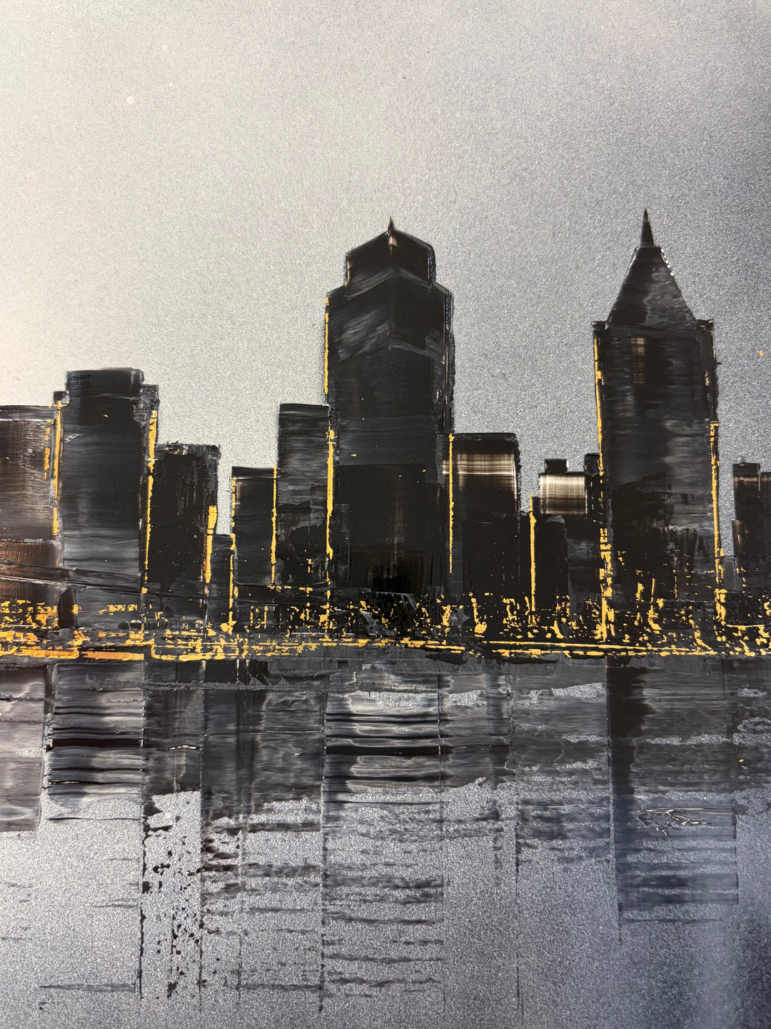 Julien Rey, Skyline, lacquer and gold leaf on board, 16 × 47 inches. Close-up detail of dark lacquered skyscrapers with gold leaf window lights reflected in the water below.