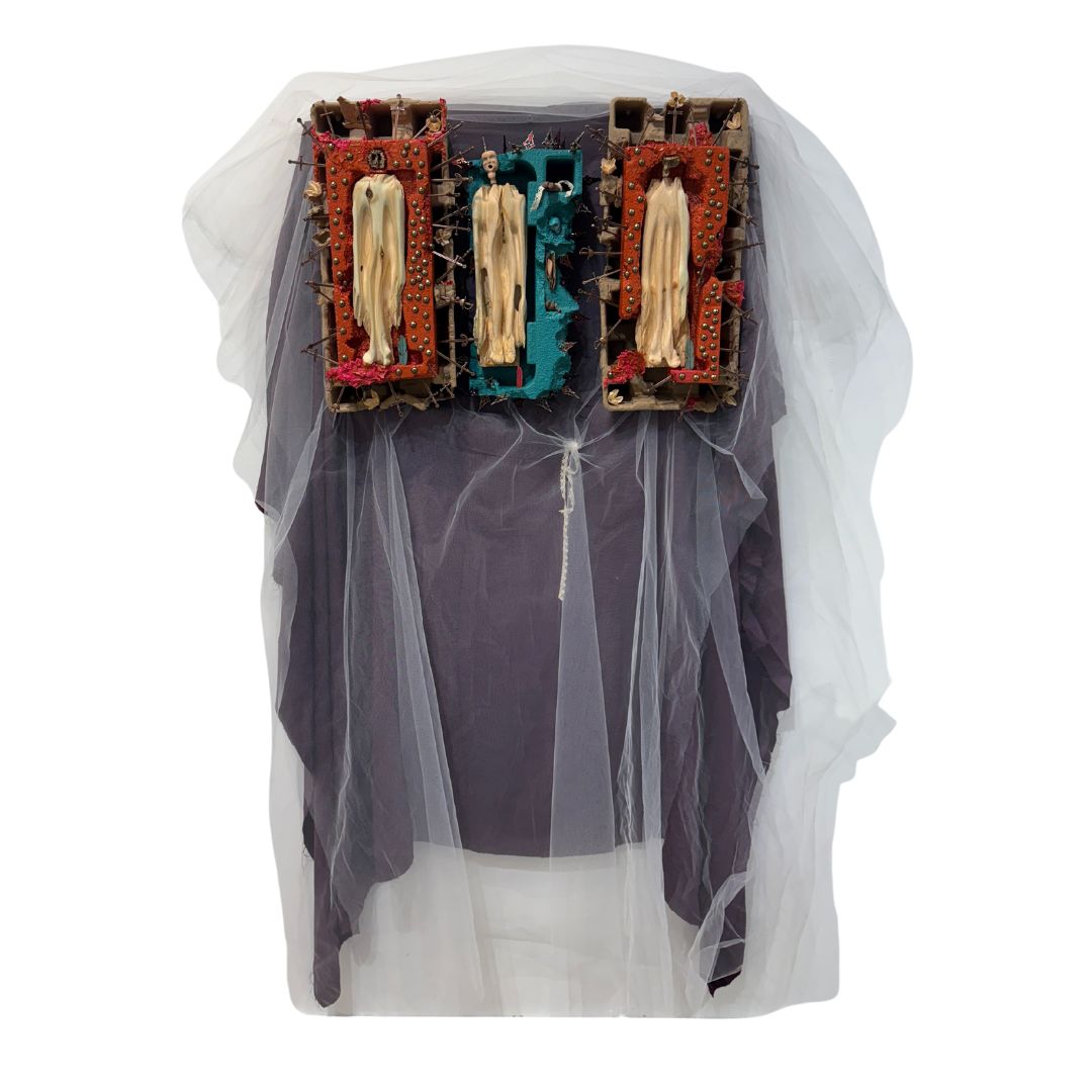 cartons with wooden carved figurines and metal sword crosses sticking out on top purple and white tulle fabric red and blue paint idols