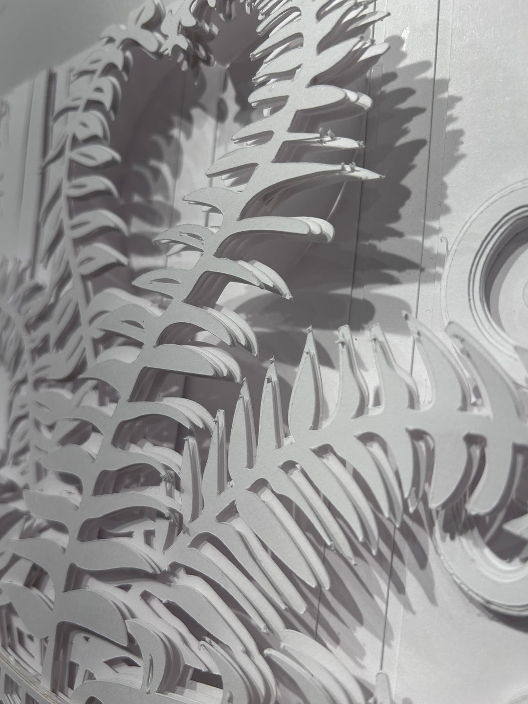 14"x14" layered white paper forming a vase with a fern over a wall.  