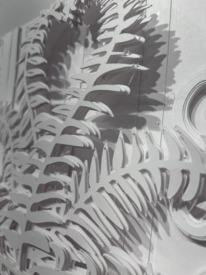 14"x14" layered white paper forming a vase with a fern over a wall.  
