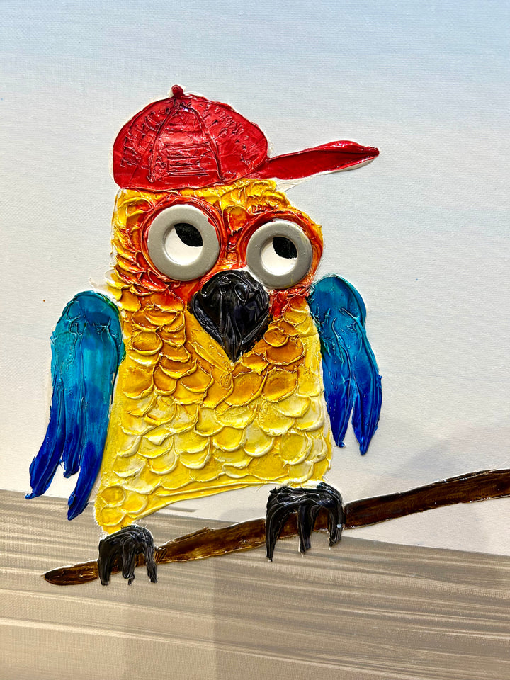 30” x 30” painting by French artist Moogly of two blue and yellow parrots with red baseball caps on a see-saw. One parrot is jumping on one end of the see-saw, making the other parrot fly up in the air. The parrots are made out of resin, giving them a textured and shiny finish. Their eyes are made out of washers that the artist has adhered to the canvas.